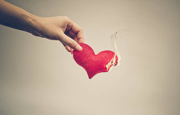 Female hand giving a heart on fire / dangerous love